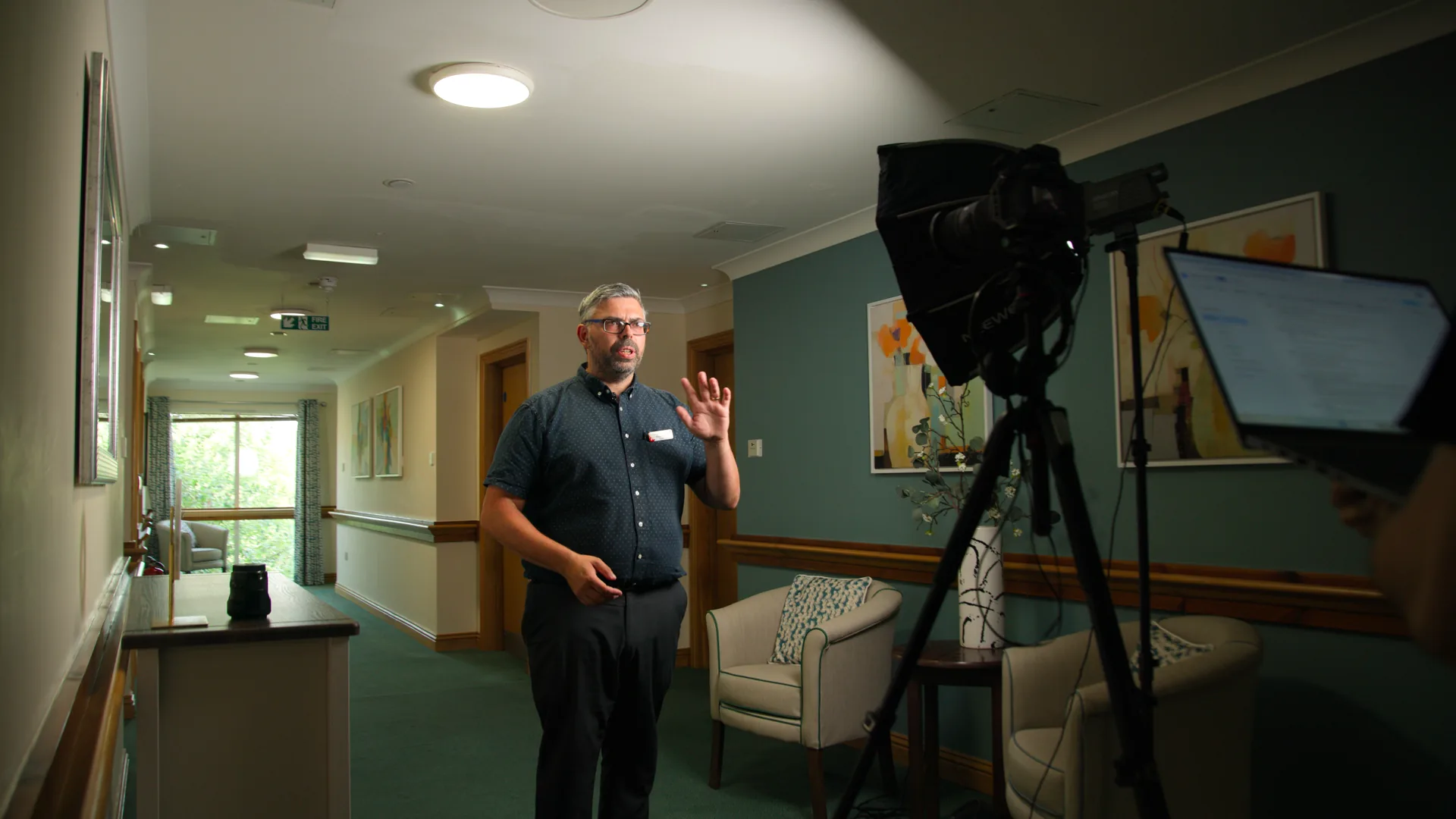 A care home manager standing in a corridor during a filming day.