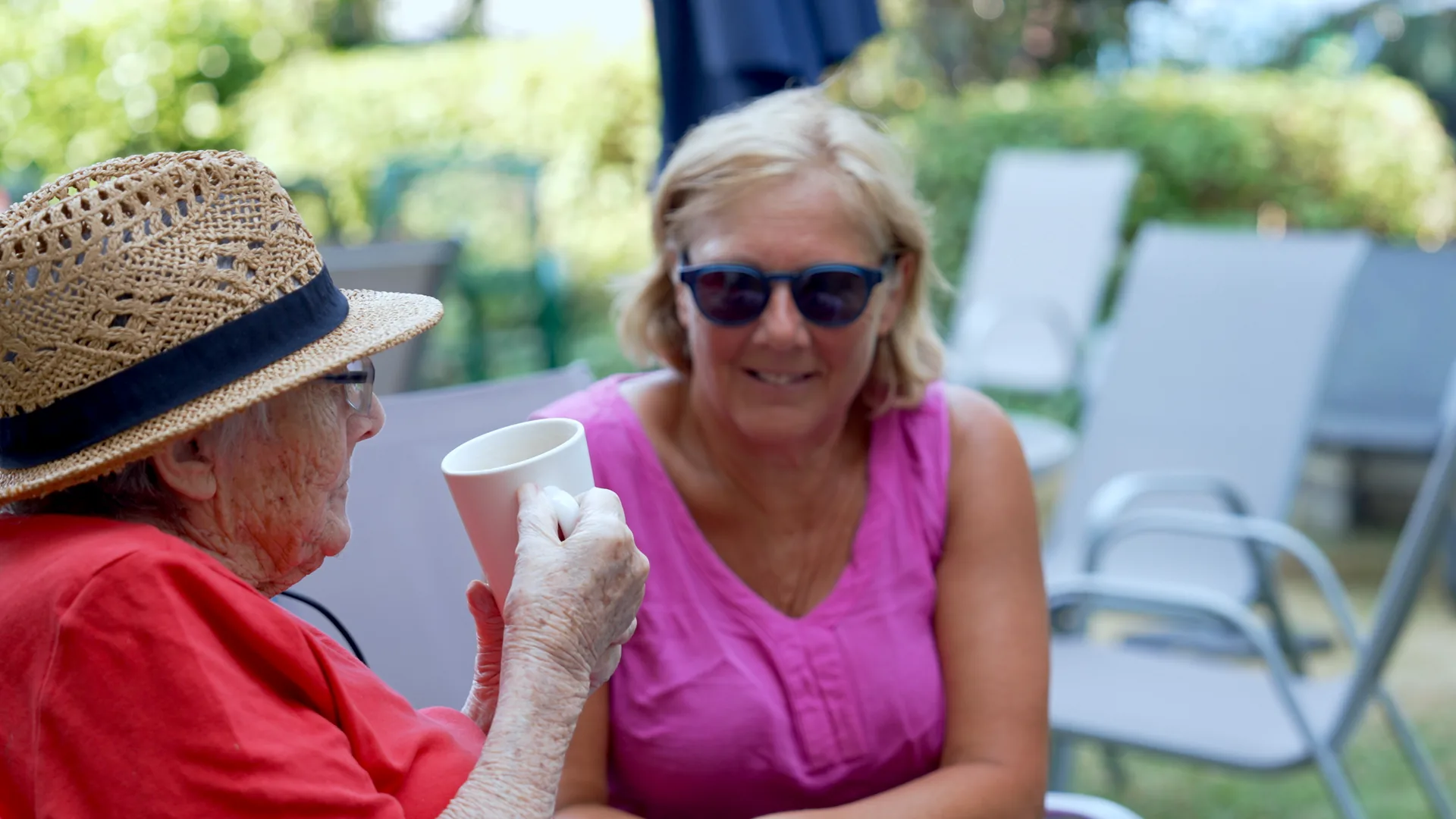 A resident and her visitor enjoying tea together in the garden.