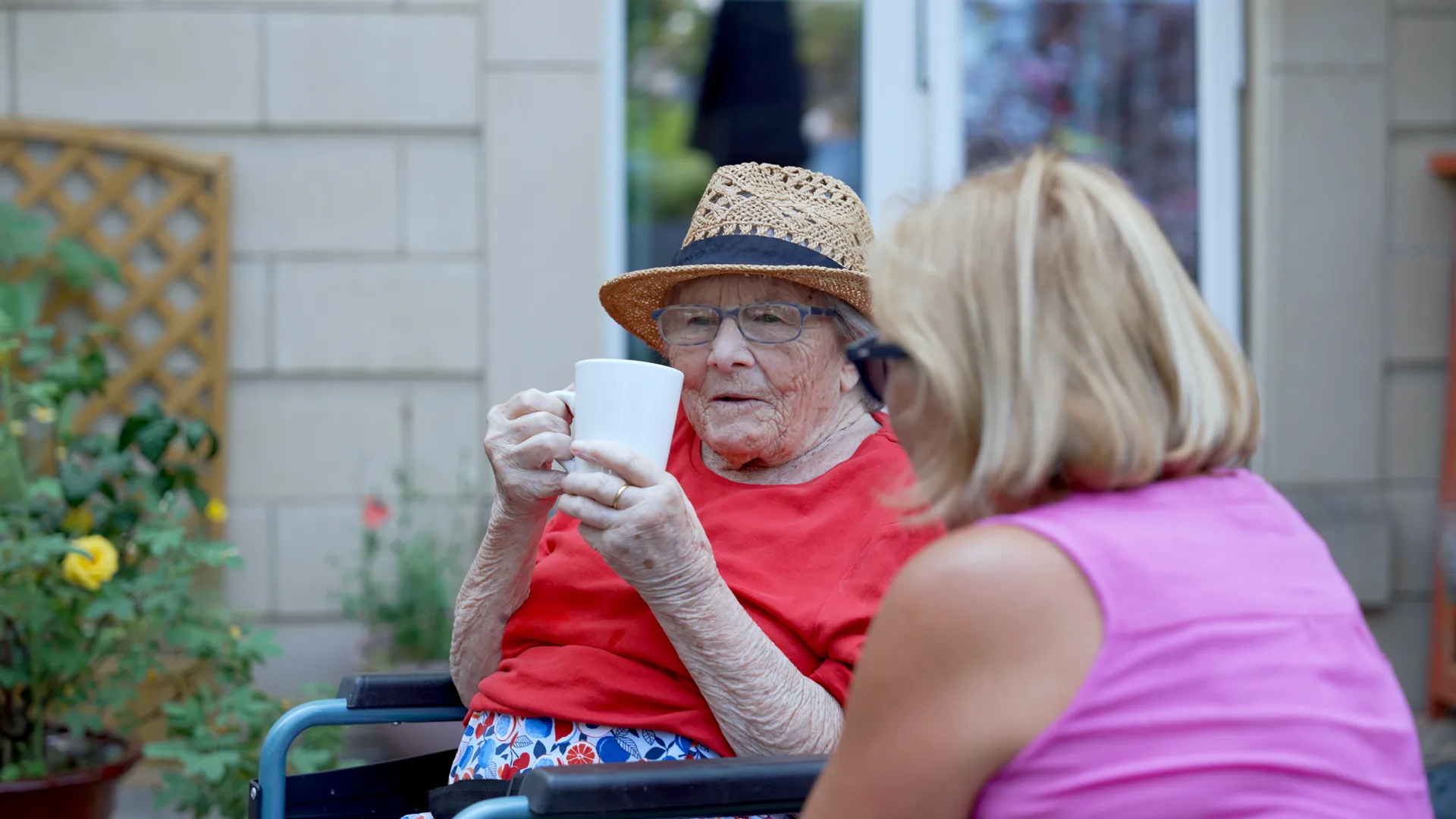 A resident enjoying tea with a visitor in the garden.