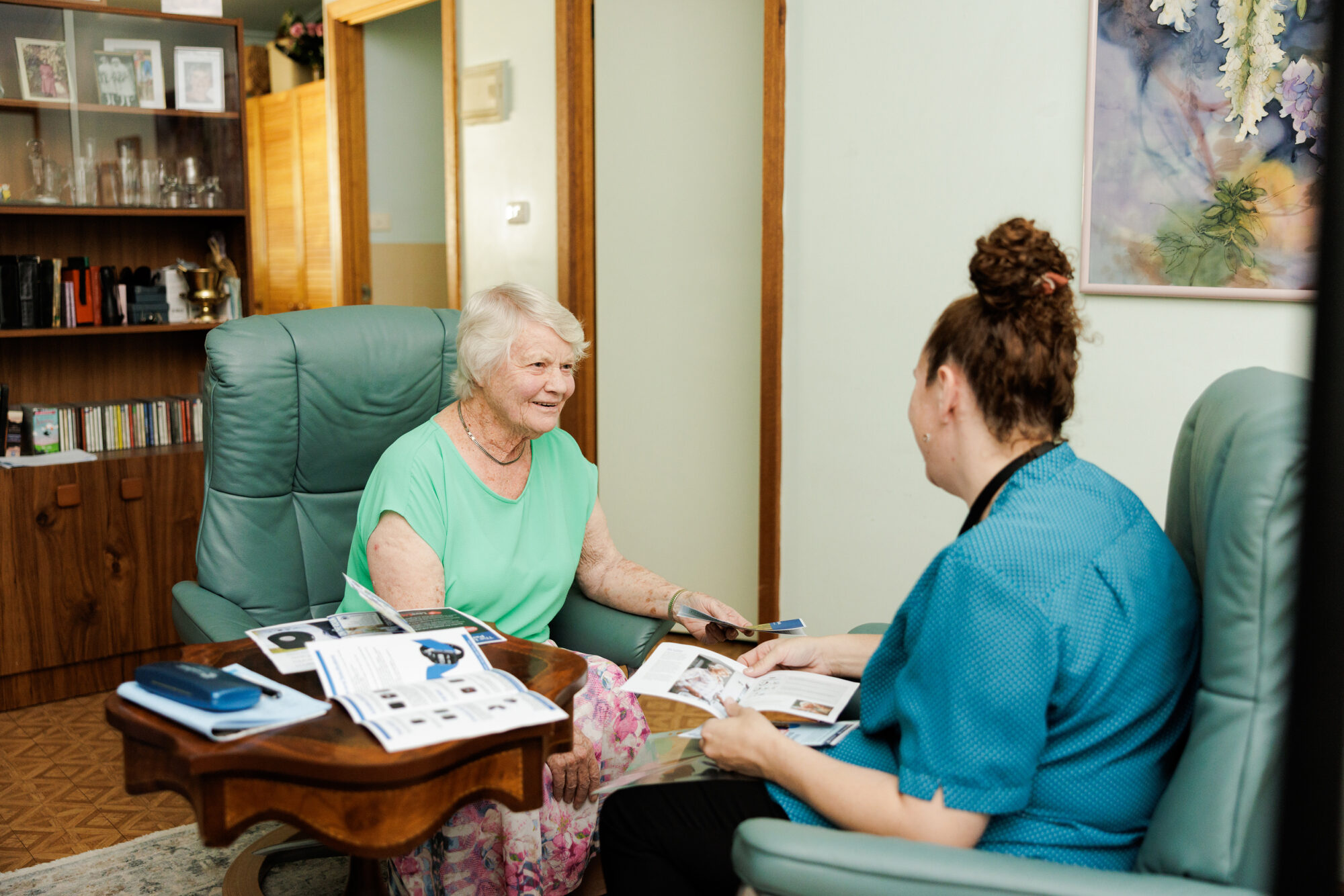 A nurse sitting and talking warmly with a care home resident.