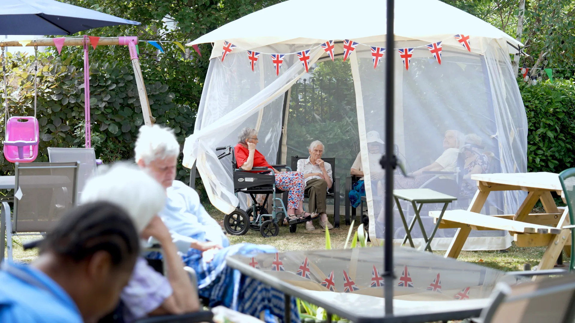 Residents and families together at a summer garden party at a care home.